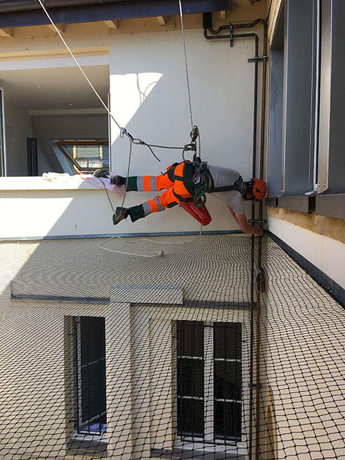 Travailleur en position acrobatique sur un bâtiment